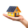 © Ina Krel - A small yellow house with solar panels on the roof resting on an open palm. Concept of sustainable energy and eco-friendly living.