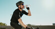 © peopleimages.com - Drinking water, fitness and cycling with man in city for triathlon challenge, electrolytes and workout. Wellness, exercise and competition with person and bike for sports, training and mockup space