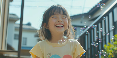 Wall Mural - A young girl is smiling and laughing while blowing bubbles. The bubbles are floating in the air and creating a joyful atmosphere