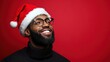 © Anastasiia K. - joyful handsome black man in santa claus hat isolated on bright red background, copy space. man in new year christmas hat