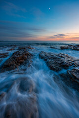 Wall Mural - Serene view of the rocky shore at dawn.