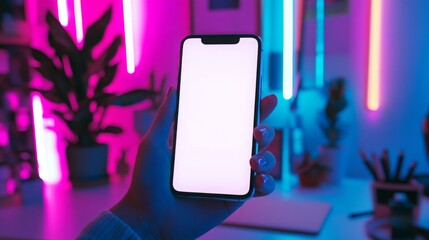 Aufkleber - A person holds a smartphone with a blank display in a colorful workspace illuminated by neon lights. The setup features glowing blue and pink hues, along with green plants in the background.