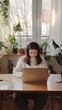 © Valeriia - Woman Working on Laptop at Home Office Desk with Plants