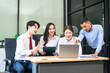 © NanSan - Two young businessmen and two beautiful women sit at a desk in the office, talking, working, watching computers, exchanging gifts, and laughing joyfully while celebrating welcoming  Happy New Year