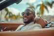© Gatherina - Businessman driving luxury convertible car wearing sunglasses and smiling