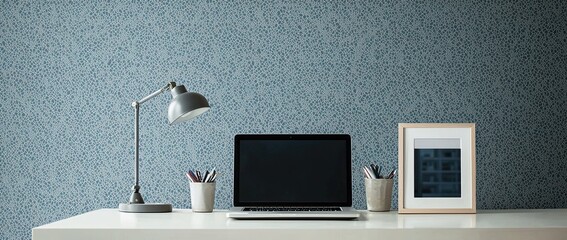 Poster - A workstation with a laptop, and desk lamp on a white table in a minimalist interior with a patterned wallpaper wall