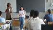 © EFStock - Asian girl college student reading project presentation to classmates and teacher at High School