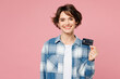 © ViDi Studio - Young cheerful happy woman she wear blue shirt white t-shirt casual clothes hold in hand mock up of credit bank card isolated on plain pastel light pink background studio portrait. Lifestyle concept.