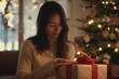 © Elena - woman smiles while wrapping a Christmas gift in front of a tree with festive lights