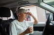 © Davor - Tired senior nurse drinking coffee in her car