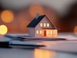 © Mandeep - a model house with illuminated windows on a desk surrounded by paperwork