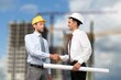 © BillionPhotos.com - construction worker with contractor shaking hands in renovation site.