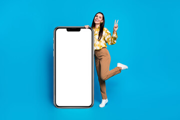 Poster - Photo of cheerful glad elegant woman wear trendy clothes presenting v-sign empty space isolated on blue color background