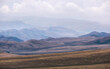 © Lana Kray - Beautiful autumn mountain landscape as a background in the steppe with dry yellow foliage, chocolate hills with haze extending into the mountains