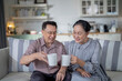 © ultramansk - An elderly couple enjoys a peaceful moment at home, sharing smiles and drinks. The warm and cozy atmosphere emphasizes their deep connection, happiness, and the comfort of spending time together.