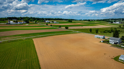 Wall Mural - Vast agricultural fields dominate the landscape, showcasing a mix of green crops and brown earth.