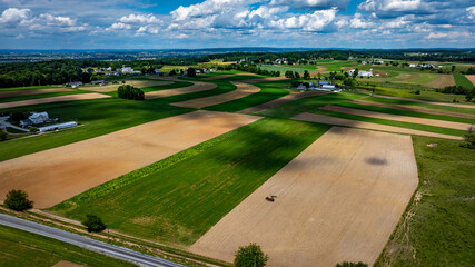 Wall Mural - Vast agricultural fields dominate the landscape, showcasing a mix of green crops and brown earth.