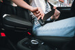 © deagreez - Young woman fastens seatbelt in car, ensuring safety with stylish casual clothing