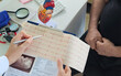 © Nadzeya - Doctor hands pointing Electro-cardiogram chart on clipboard pad fill medical history with pen