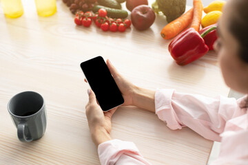 Aufkleber - Breakfast Concept. Over the shoulder above view of young female holding in hand device with black empty screen for mock up design, checking email or browsing internet sitting at dinner table