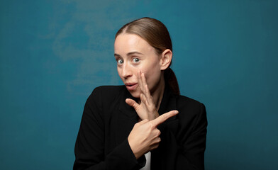 Wall Mural - feeling surprised with a shocked expression and pointing to the side