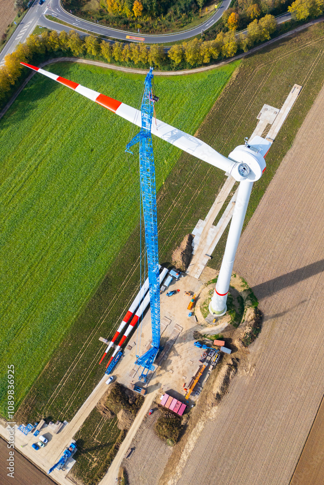 Wind power plant construction site. Massive crane is installing rotor ...