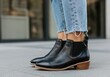 © Yulia - Stylish black leather ankle boots paired with frayed hem jeans outdoors