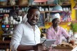 © darshika - Smiling African entrepreneur at cafe counter using digital tablet