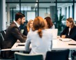© NRdS - A softly blurred image depicts a group of business professionals gathered around a sleek table in a modern, open-concept office
