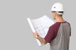 © Pixel-Shot - Young male engineer with blueprint on grey background