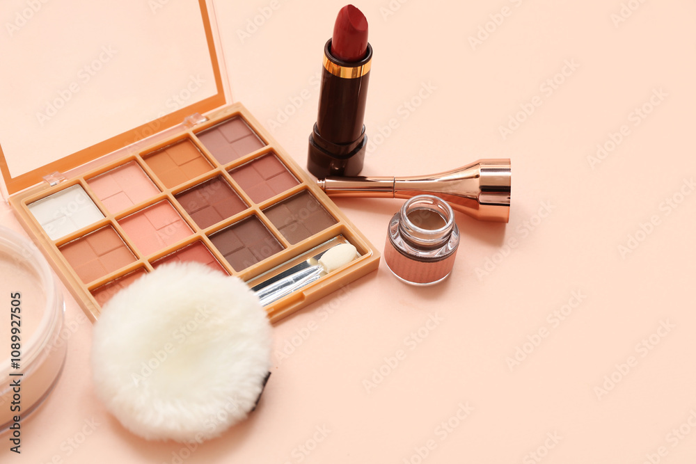 Eyeshadows palette with eyeliner, powder and lipstick on beige background