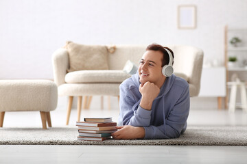 Wall Mural - Young man listening audiobook and lying on floor in living room