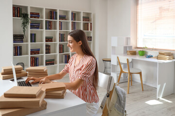 Wall Mural - Happy female student with laptop and books studying in library