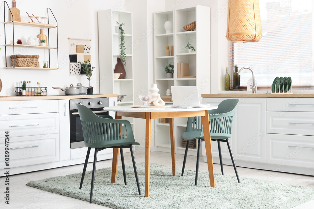 White dining table with laptop and magazines in interior of kitchen