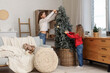 © Pixel-Shot - Cute sisters decorating Christmas tree at home