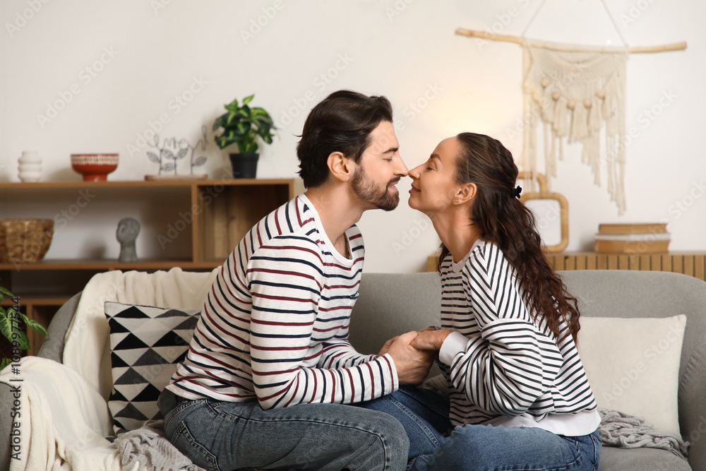 Married couple touching noses on sofa at home
