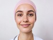 © Matt - Bright and cheerful young woman in a pastel pink headscarf and a white coat, smiling warmly at the camera