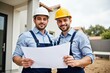 © SimpleDesignStudio - Professional Construction Workers Reviewing Plans at Job Site, Ideal for Business Marketing or Training Materials