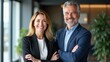 © useful pictures - A man and woman, dressed in business attire, stand together in a bright office. They exude confidence and professionalism, embodying teamwork in a lively workspace