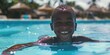 © vefimov - A young boy enjoys a swim in clear pool water under tropical sunlight.