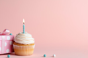 Wall Mural - delicious cupcake with lit birthday candle sits beside pink polka dot gift box on pastel background, creating festive and cheerful atmosphere