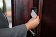© DragonImages - Hand holding key card and using it for security access control on electronic door lock in residential or commercial building. Ensuring access and security