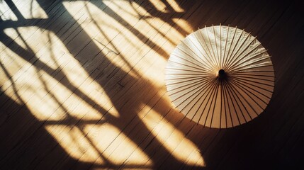 Poster - Elegant Japanese Umbrella Casting Soft Shadows on Wooden Floor with Natural Light Creating an Artistic Atmosphere in a Serene Ambience