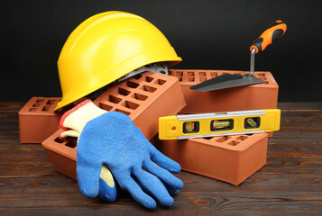 Wall Mural - Red bricks, different construction tools and safety equipment on wooden table