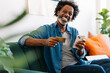 © (JLco) Julia Amaral - Online shopping: Mature black man using an ecommerce app on his smartphone at home
