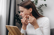 © Yura Yarema - Worry young woman sitting on couch stressed looking in mirror, allergy presenting allergic reaction from cosmetic on face. Beauty, health care from acne problem, dry skin, treatment concept