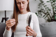 © Yura Yarema - Close up of sad young caucasian woman holding comb show hairbrush with hair loss in brush after brushing fall sitting alone on sofa at home. Problem hair, health care, beauty with treatment concept