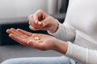 © Yura Yarema - Close up of sick young woman holding tablet pills sitting on sofa, painkiller medicine from stomach pain, headache, pain for treatment, take drug or vitamin at home, health care concept