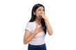 © Sewupari Studio - Disgusted young Asian woman pinching her nose while holding her chest, expressing discomfort and reaction to a bad smell on white background