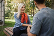 © arthurhidden - A couple sits on a park bench having a cheerful conversation on a sunny day. The woman smiles warmly, creating a relaxed and positive atmosphere in the lush green environment.